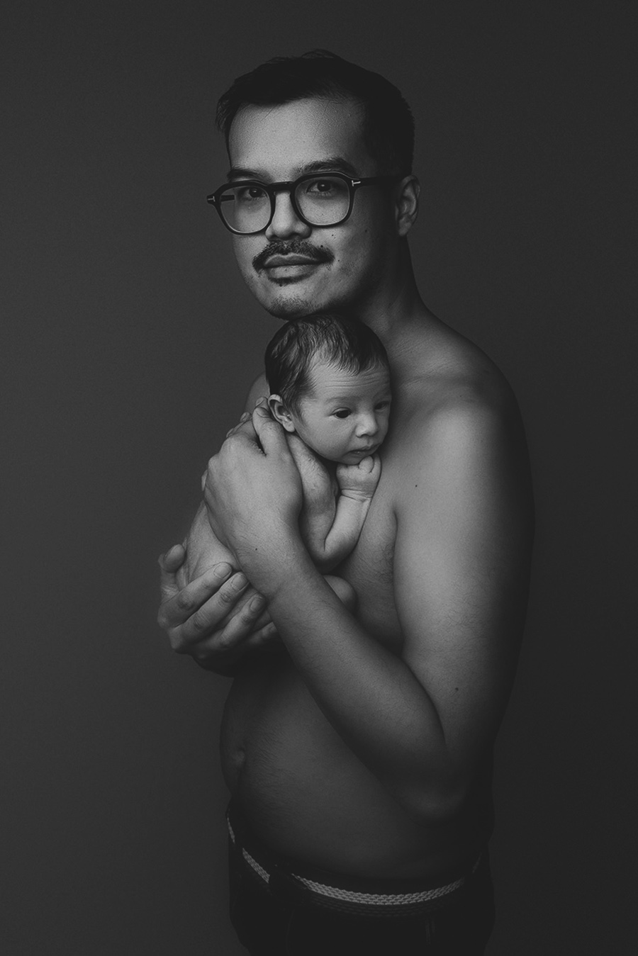 shooting d'un papa qui porte son bébé lors d'une séance photo naissance en studio sur Bondues près de Lille